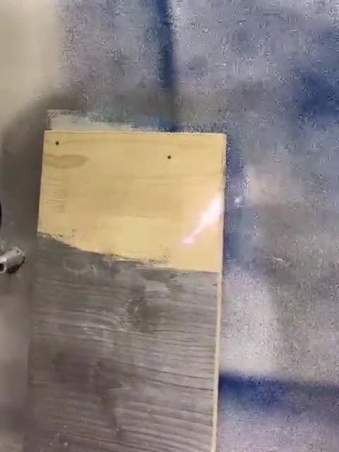 Holzbrett mit freigelegter heller Fläche neben grauem Anstrich